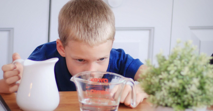 child with measuring cup of water